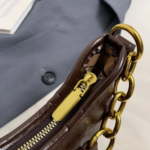 Détail macro du sac en cuir marron foncé avec fermeture éclair dorée et chaîne