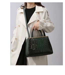 Close-up of dark green crocodile embossed leather handbag with gold metal hardware