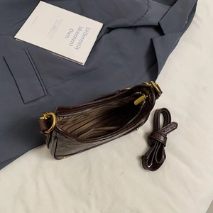 Détail du sac croissant vintage marron avec texture matelassée et fermeture éclair dorée