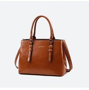 Detail view of glossy caramel brown tote bag with dual handles and long shoulder strap