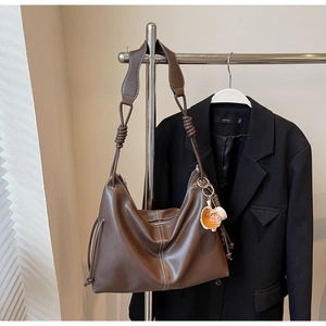 Detail of dark brown matte Hobo bag featuring a wide knotted strap and a glove charm