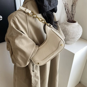 Détail du sac croissant crème avec cuir plissé, chaîne dorée et rivets métalliques