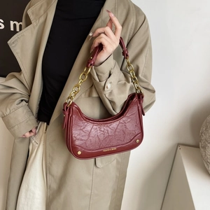 Détail du sac croissant rouge vin avec cuir plissé et bandoulière en chaîne dorée