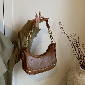 Vue détaillée du sac hobo croissant en cuir marron avec chaîne dorée et poignée en cuir
