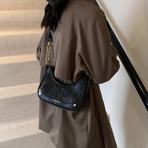 Détail du sac hobo croissant noir avec chaîne dorée et texture cuir froissé