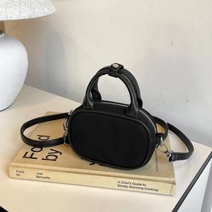 Detail of a black mini crossbody bag with round handles on a vintage book