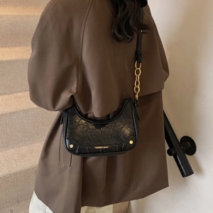 Détail du sac croissant noir vintage avec chaîne dorée et cuir à l'aspect texturé