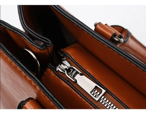 Detail of silver zipper closure and interior compartment of brown leather tote bag