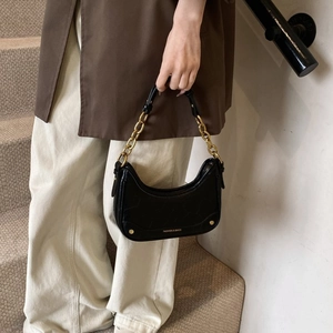 Détail du sac croissant noir en cuir embossé crocodile avec poignée en chaîne dorée