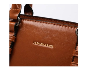 Detailed close-up of brown oiled leather texture with gold foil stamped logo and stitching