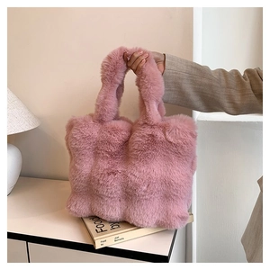 Close-up of pink faux fur plush shoulder bag with dual handles in a cozy indoor setting