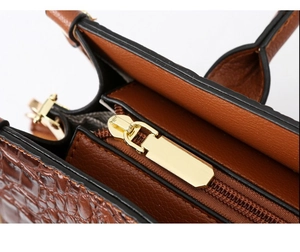Detail of dark brown crocodile pattern leather tote with light gold polished zipper