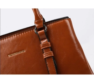 Close-up of brown faux leather texture with fine stitching and metallic handle loops