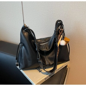 Minimalist black leather tote bag with baseball pendant on business layout background