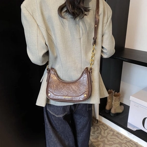 Détail du sac croissant marron foncé montrant la texture en simili cuir et rivets dorés