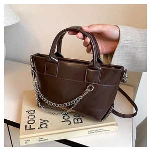 Détail du sac en cuir marron foncé avec chaîne argentée et bandoulière amovible