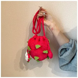 Dettaglio di borsa in maglia fatta a mano con trama dragon fruit e ciondolo a fetta