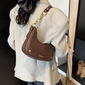 Détail du sac croissant marron foncé avec chaîne dorée et inscription à la mode