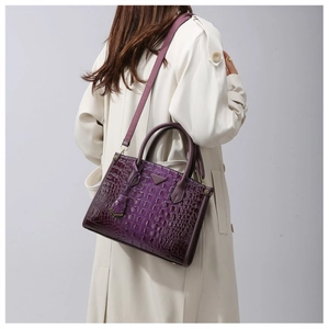 Detail of a dark purple crocodile pattern tote bag shown with a white trench coat