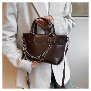 Détail du sac à main en cuir marron foncé avec chaîne argentée et bandoulière réglable