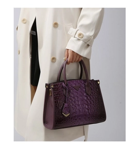 Detail of purple crocodile-patterned tote bag with polished finish and metal pendant
