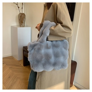 Detail of light blue faux fur tote bag with wavy texture carried by a model