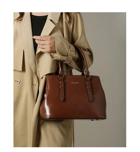 Detail of dark brown glossy leather tote bag with metallic buckle and fashion branding