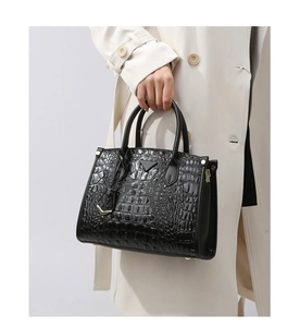Detail of black crocodile-embossed handbag featuring triangle logo and metal zipper