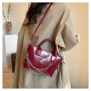 Détail montrant la texture du cuir bordeaux et la chaîne en argent du sac