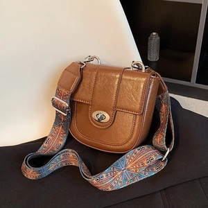 Detail of caramel leather shoulder bag with silver turn-lock and colorful ethnic strap