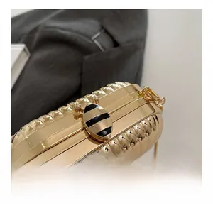 Detail of golden metal party bag with wavy texture and striped insect clasp buckle