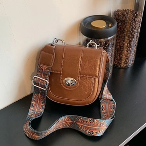 Detailed view of brown leather crossbody bag featuring a colorful ethnic woven strap