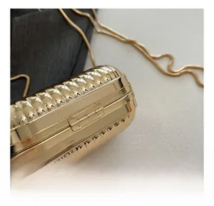 Detail of golden evening bag showing the metal hinge texture and sleek snake chain strap