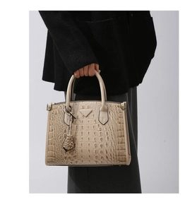 Close-up of beige crocodile pattern tote bag featuring metallic triangle plaque
