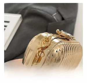 Close-up of golden metal evening bag with vertical stripe texture and hardware details