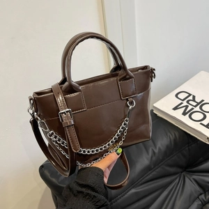 Détail d'un sac à main en cuir marron foncé brillant avec chaîne argentée et poignée