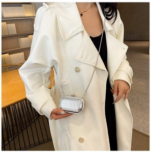 Silver metallic capsule chain bag styled with a white coat in an indoor library setting