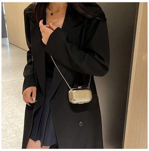 Close-up of gold metallic evening bag with vertical pleated texture and thin chain strap