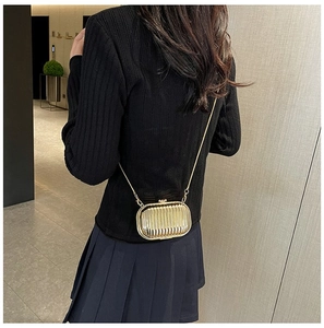 Detailed view of a gold metallic mini hardshell crossbody bag with vertical striped texture