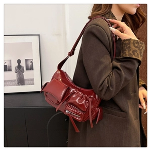 Détail du sac hobo en cuir verni rouge foncé avec poches vintage et zips argentés