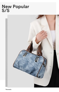 Detail of denim crossbody bag with brown leather handles worn with a white blazer