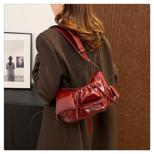 Sac bandoulière style motard en cuir verni bordeaux avec plis et détails zippés