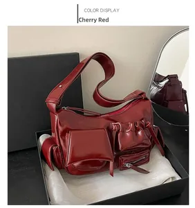 Détail du sac bandoulière rouge cerise avec multiples zips dans son coffret cadeau
