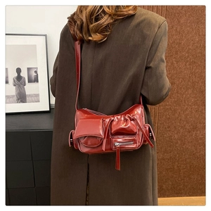 Détail du sac bandoulière en cuir ciré rouge foncé avec poches utilitaires fonctionnelles