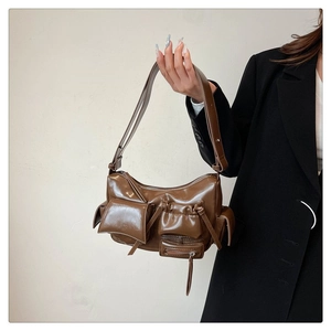 Détail du sac en cuir marron foncé brillant avec poches fonctionnelles et bandoulière