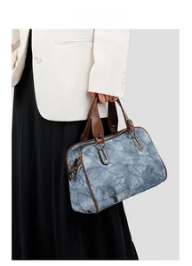 Close-up of denim patchwork pattern with brown leather handles on a casual tote bag