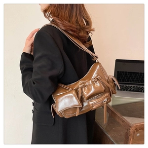 Gros plan sur un sac porté épaule marron brillant avec poches avant et fermetures éclair