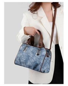 Blue denim crossbody bag styled with brown leather straps on a white suit model