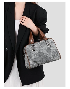 Detail of vintage denim Boston bag with grey washed texture and brown leather handles