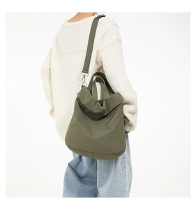 Detail der armee-grünen Nylon-Tote-Bag mit Plissee-Textur und verstellbarem Gurt am Modell